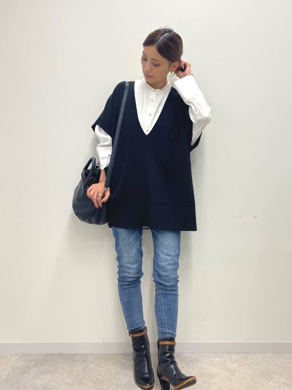 ブラック系のニット/セーター、ホワイト系のシャツ/ブラウス、ブラック系のショルダーバッグを着用したレディースの夏コーディネートの2枚目の写真