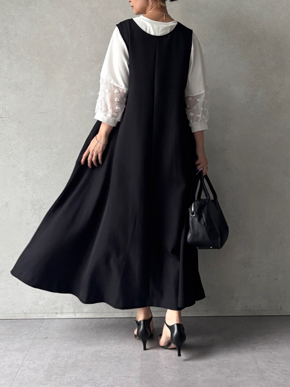 ブラック系のワンピース、ホワイト系のTシャツ/カットソー、ブラック系のショルダーバッグを着用したレディースの春コーディネートの4枚目の写真