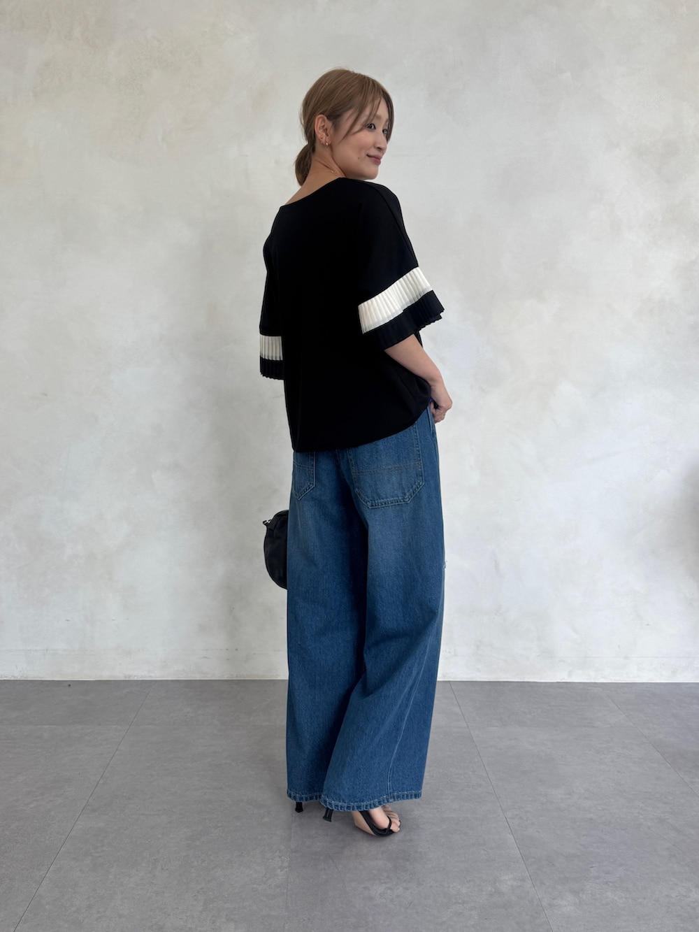 ブラック系のTシャツ/カットソー、ブルー系のその他パンツ、ブラック系のボストンバッグを着用したレディースの春コーディネートの2枚目の写真