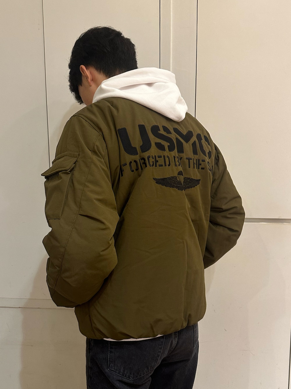 グリーン系のブルゾン、ホワイト系のパーカーを着用したメンズの秋コーディネートの3枚目の写真