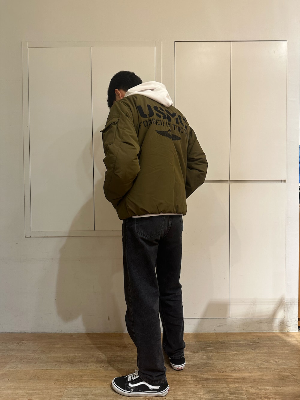 グリーン系のブルゾン、ホワイト系のパーカーを着用したメンズの秋コーディネートの2枚目の写真