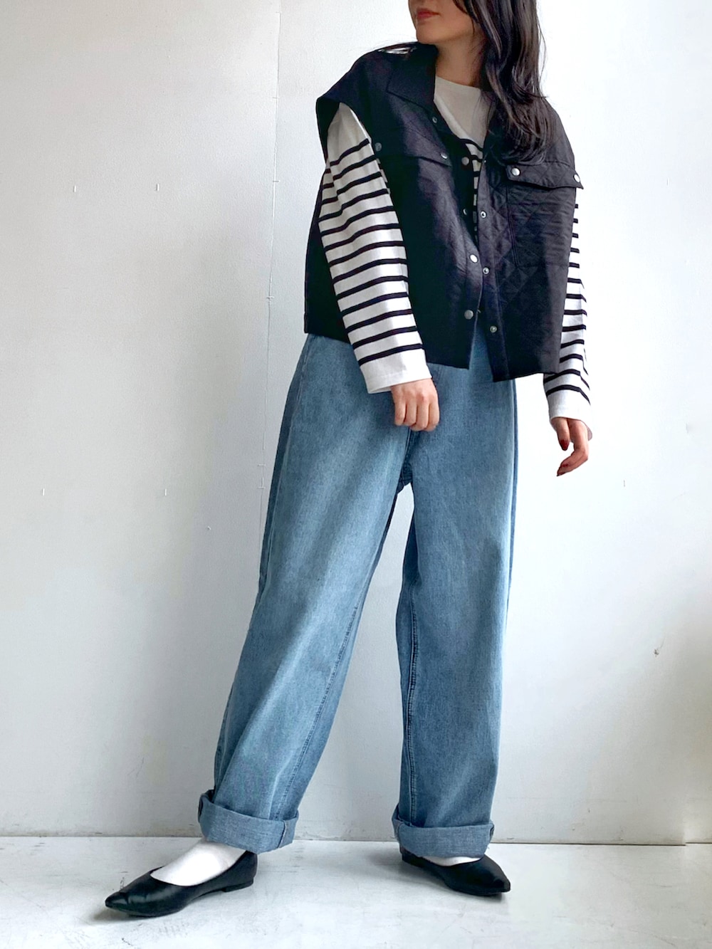ホワイト系のTシャツ/カットソー、ブラック系のベスト、ブルー系のデニムパンツを着用したレディースの春コーディネートの2枚目の写真