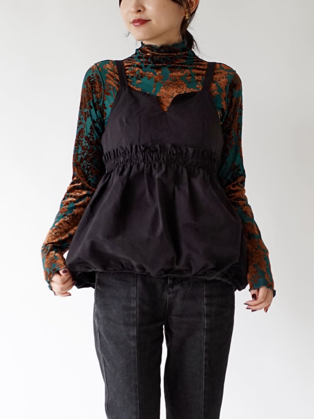 グリーン系のTシャツ/カットソー、ブラック系のキャミソール、ブラック系のデニムパンツを着用したレディースの秋コーディネートの3枚目の写真