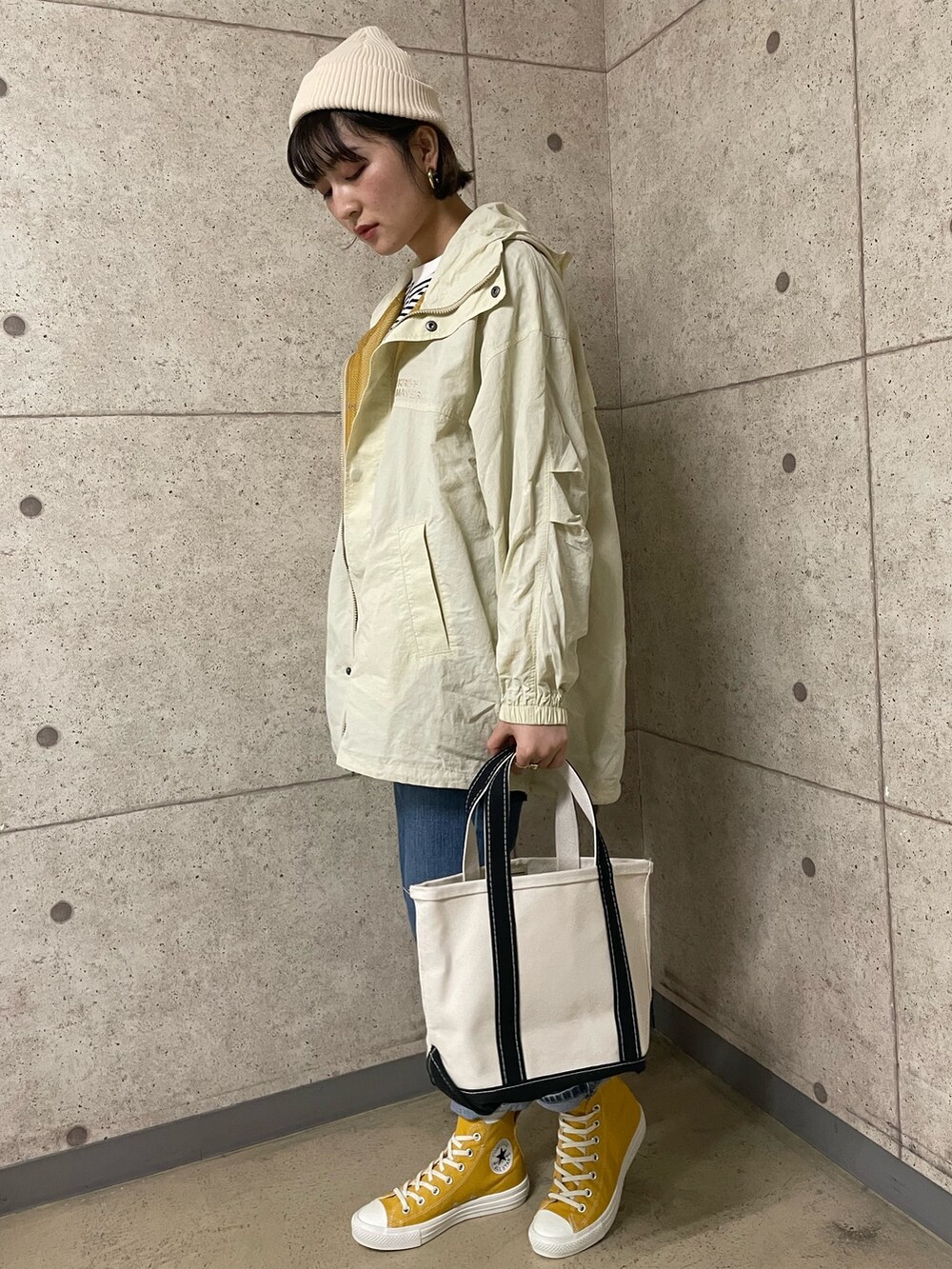 ベージュ系のマウンテンパーカー、イエロー系のスニーカー、ブルー系のデニムパンツを着用したレディースの春コーディネートの2枚目の写真