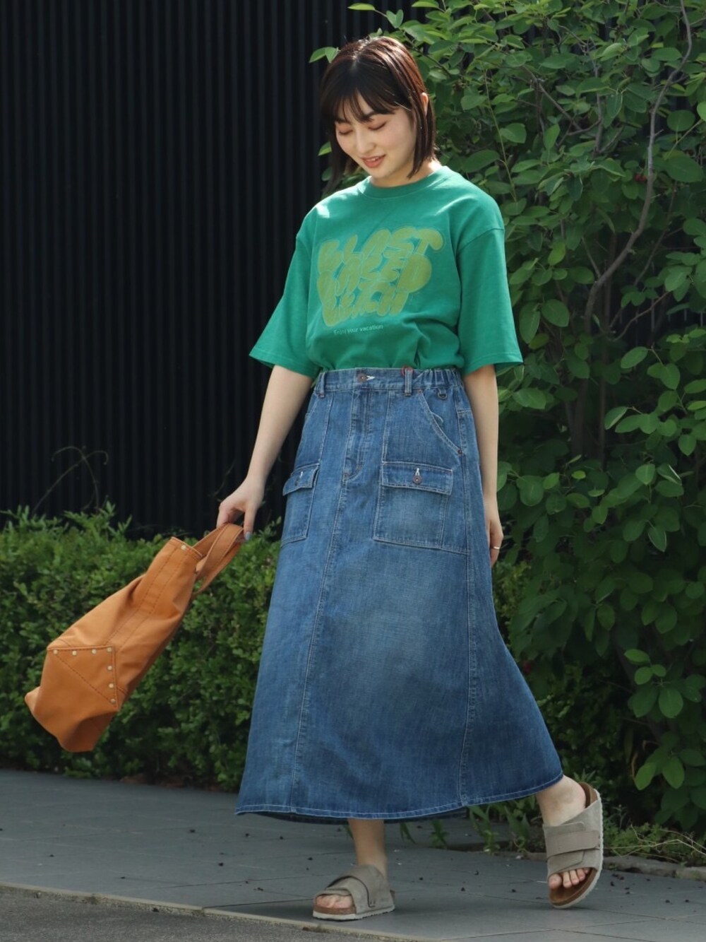 グリーン系のTシャツ/カットソー、ブルー系のデニムスカートを着用したレディースの春コーディネートの2枚目の写真