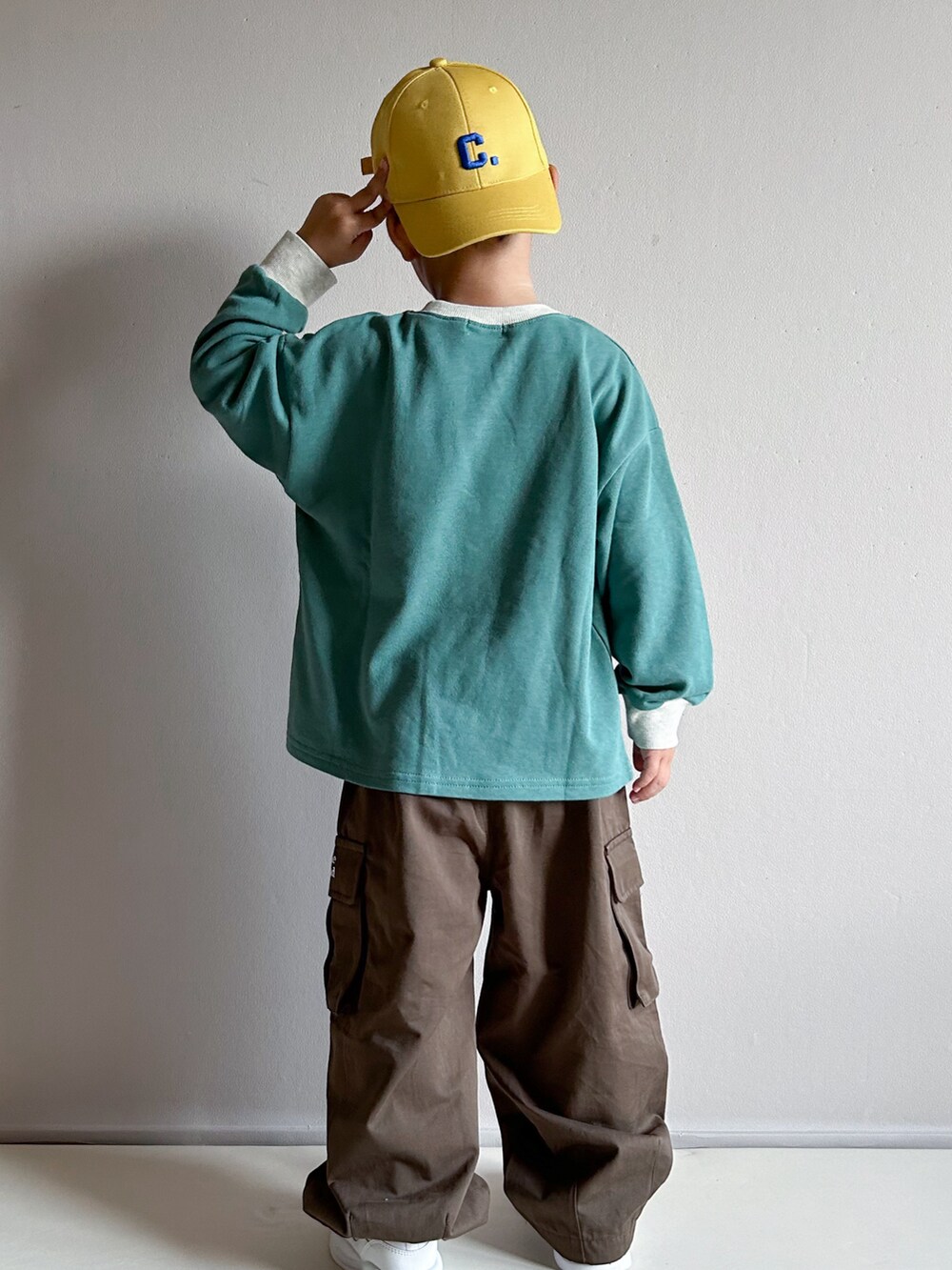 グリーン系のスウェット、ベージュ系のカーゴパンツ、ホワイト系のスニーカーを着用したキッズの秋コーディネートの4枚目の写真