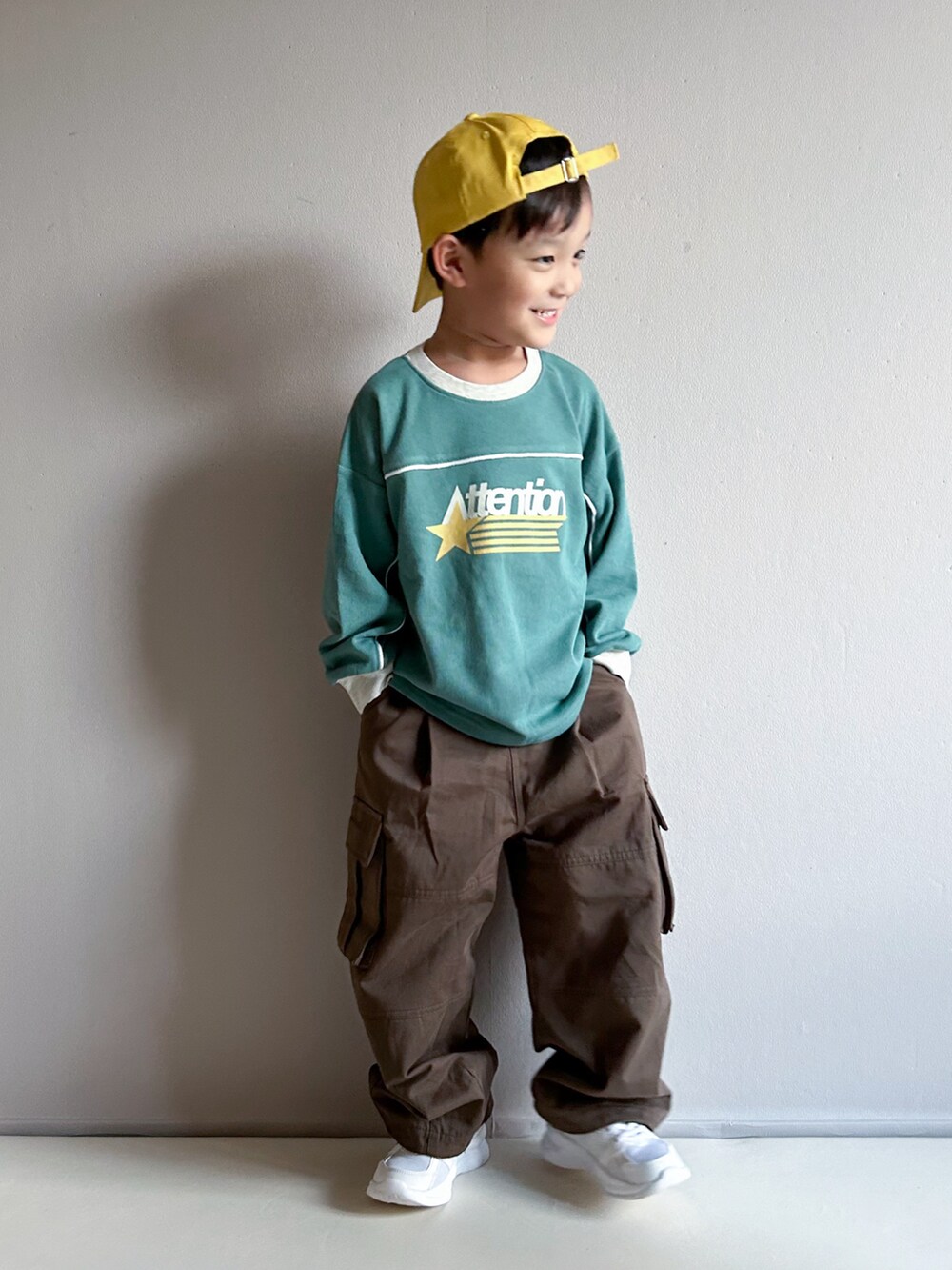 グリーン系のスウェット、ベージュ系のカーゴパンツ、ホワイト系のスニーカーを着用したキッズの秋コーディネートの2枚目の写真