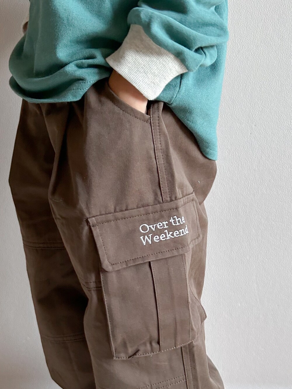 グリーン系のスウェット、ベージュ系のカーゴパンツ、ホワイト系のスニーカーを着用したキッズの秋コーディネートの3枚目の写真