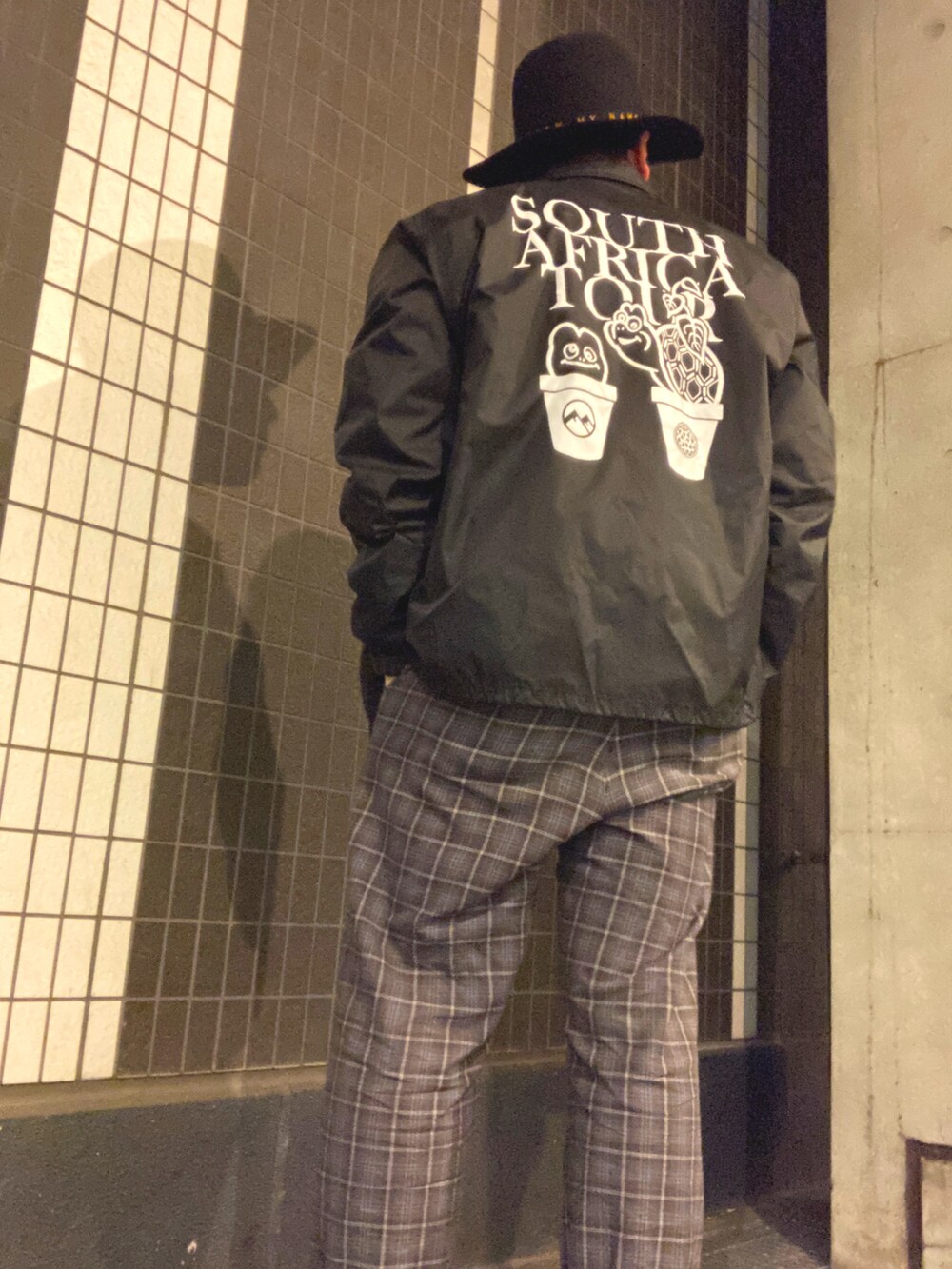 グレー系のその他パンツ、レッド系のスニーカー、ブラック系のナイロンジャケットを着用したメンズの秋コーディネートの2枚目の写真