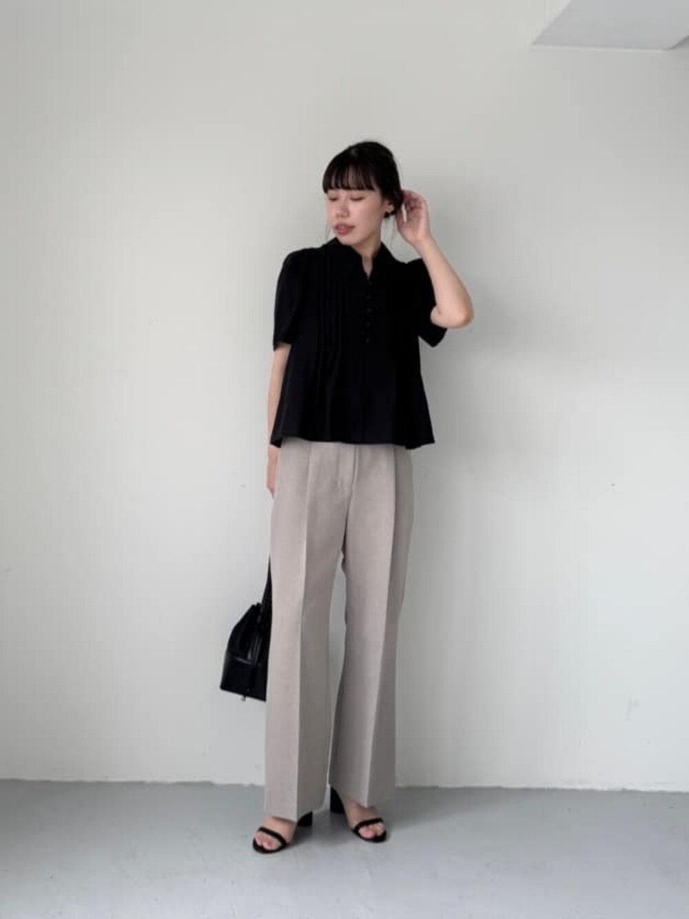 ブラック系のショルダーバッグ、ブラック系のサンダル、ベージュ系のスラックスを着用したレディースの夏コーディネートの4枚目の写真