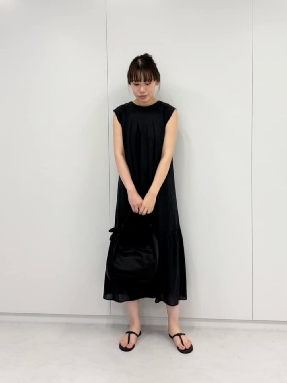 ブラック系のショルダーバッグ、ブラウン系のサンダル、ブラック系のワンピースを着用したレディースの夏コーディネートの2枚目の写真