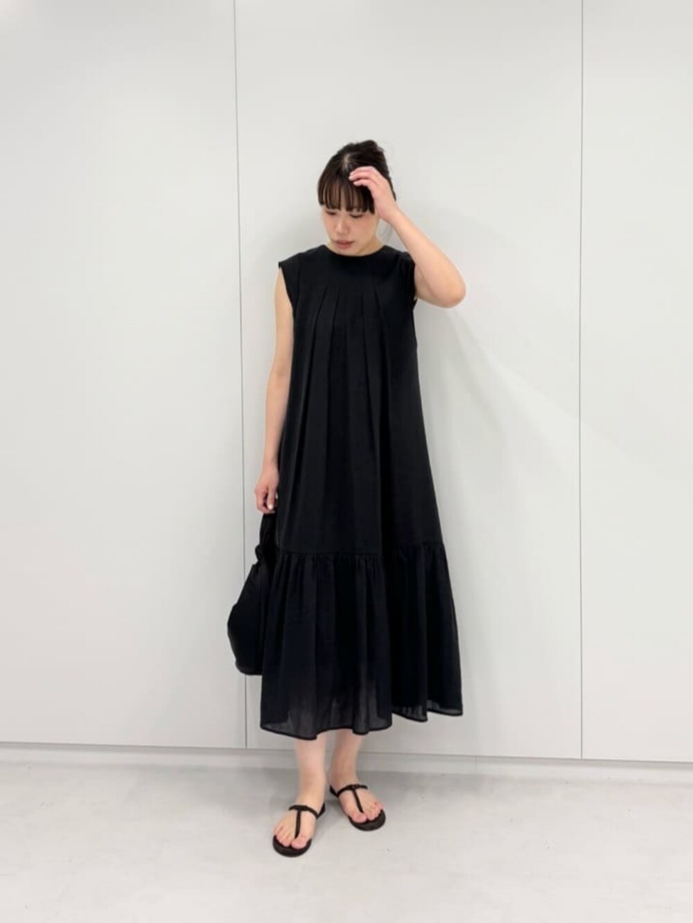 ブラック系のショルダーバッグ、ブラウン系のサンダル、ブラック系のワンピースを着用したレディースの夏コーディネートの3枚目の写真