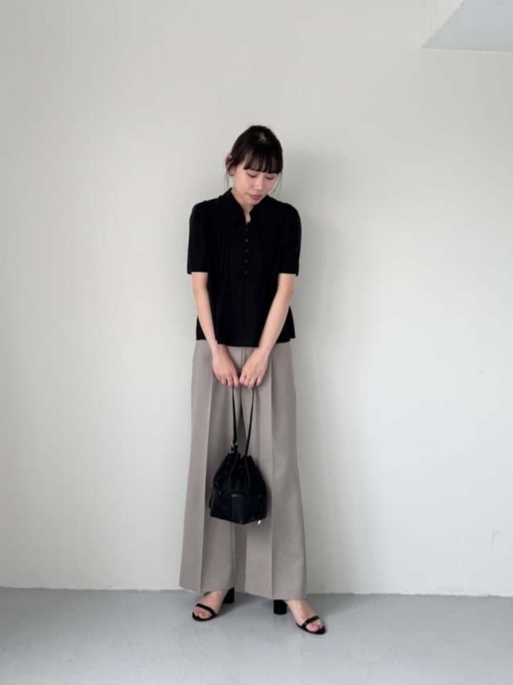 ブラック系のショルダーバッグ、ブラック系のサンダル、ベージュ系のスラックスを着用したレディースの夏コーディネートの3枚目の写真