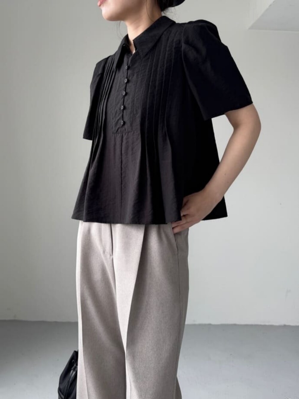 ブラック系のショルダーバッグ、ブラック系のサンダル、ベージュ系のスラックスを着用したレディースの夏コーディネートの2枚目の写真