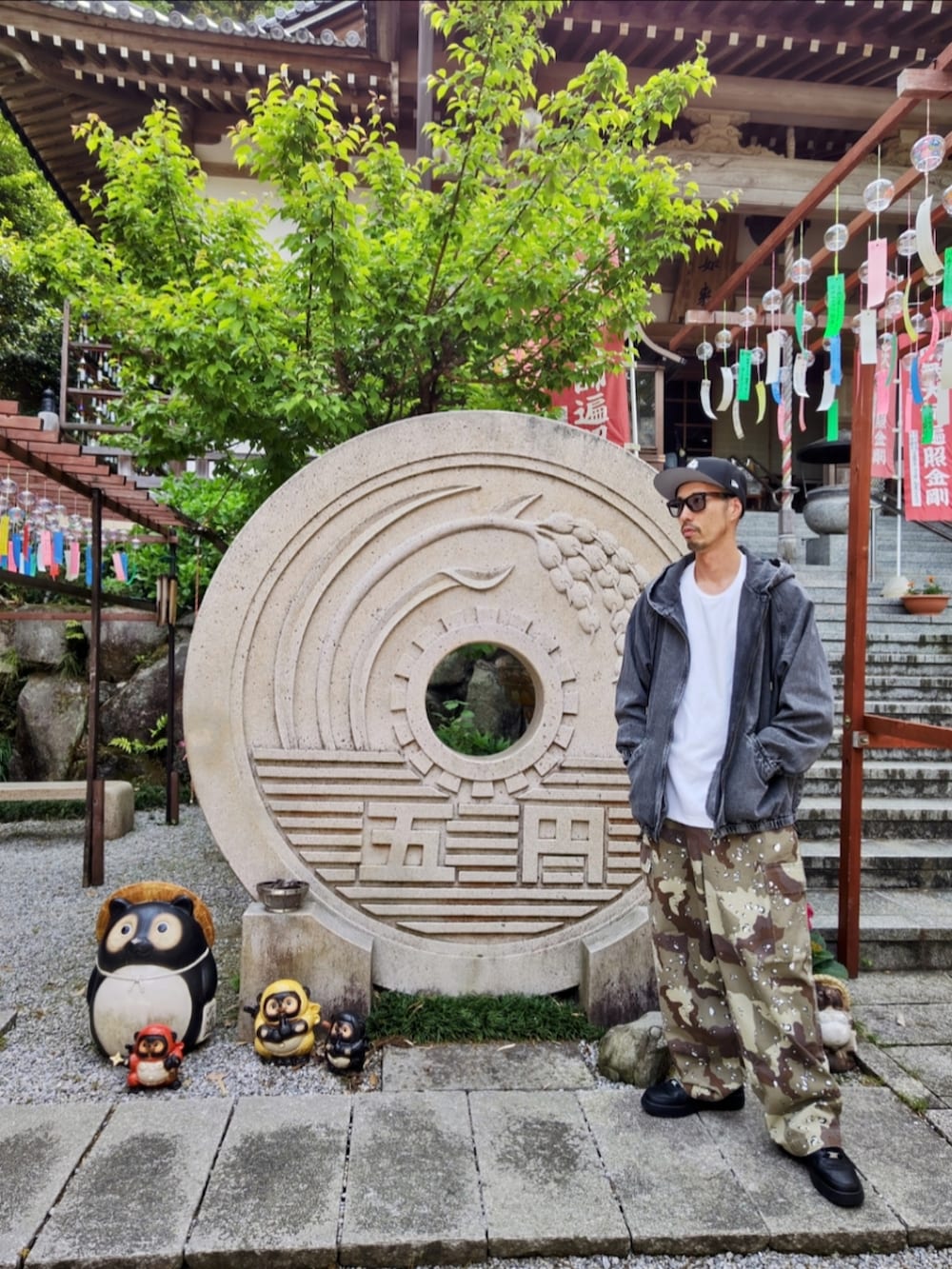 ブラック系のデニムジャケット、グリーン系のカーゴパンツ、ブラック系のスニーカーを着用したメンズの春コーディネートの3枚目の写真