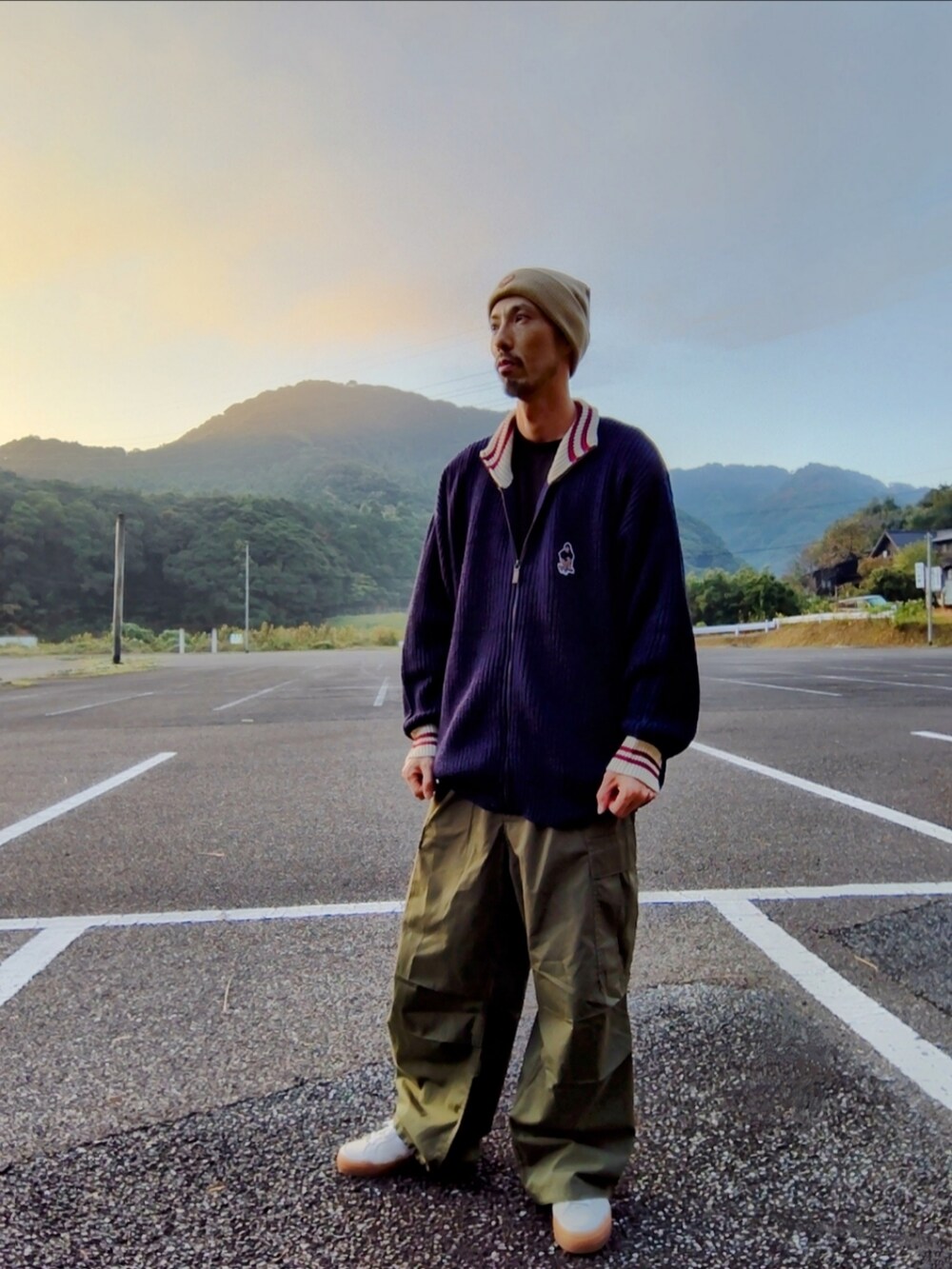 ブルー系のニット/セーター、グリーン系のカーゴパンツ、ホワイト系のスニーカーを着用したメンズの秋コーディネートの2枚目の写真