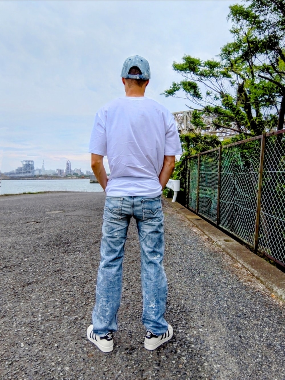 ブルー系のデニムパンツ、ホワイト系のスニーカー、ホワイト系のTシャツ/カットソーを着用したメンズの夏コーディネートの2枚目の写真