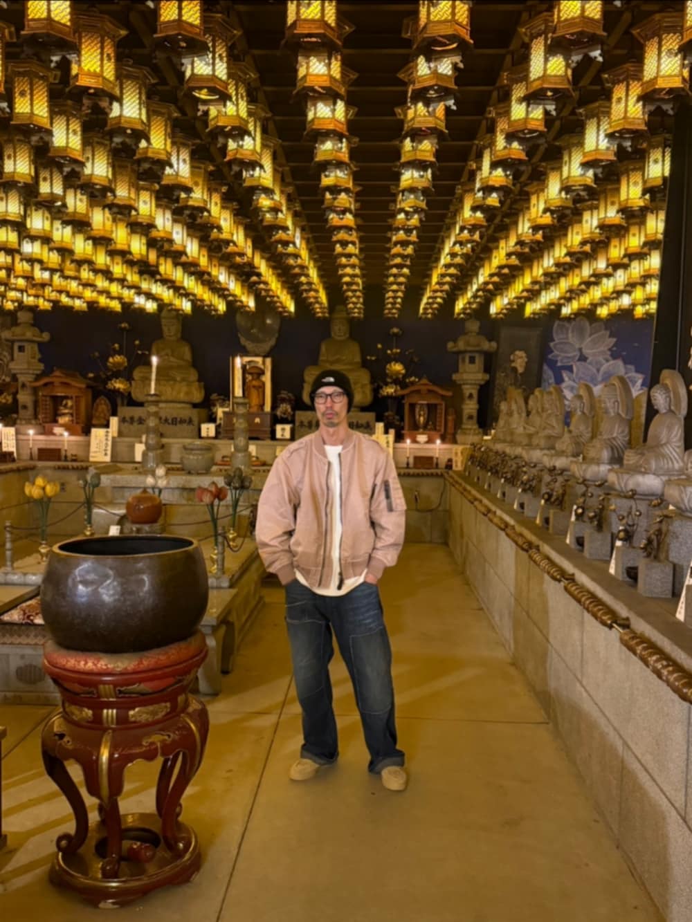 ピンク系のミリタリージャケット、ブルー系のデニムパンツ、ベージュ系のスニーカーを着用したメンズの春コーディネートの2枚目の写真