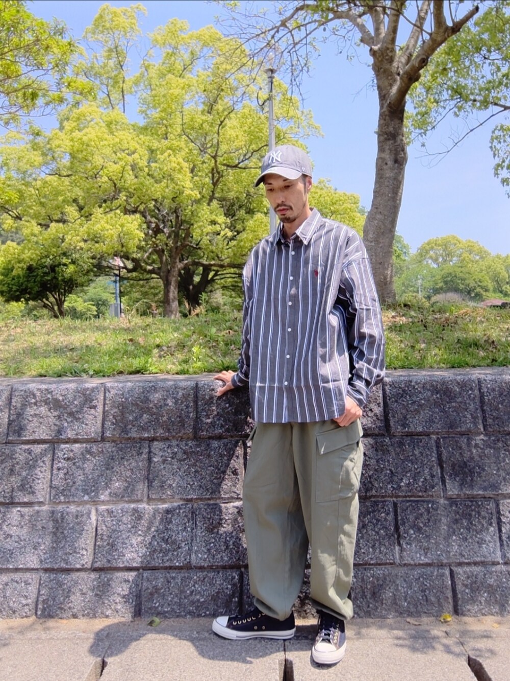 ブラック系のシャツ/ブラウス、グリーン系のカーゴパンツ、ブルー系のスニーカーを着用したメンズの春コーディネートの2枚目の写真