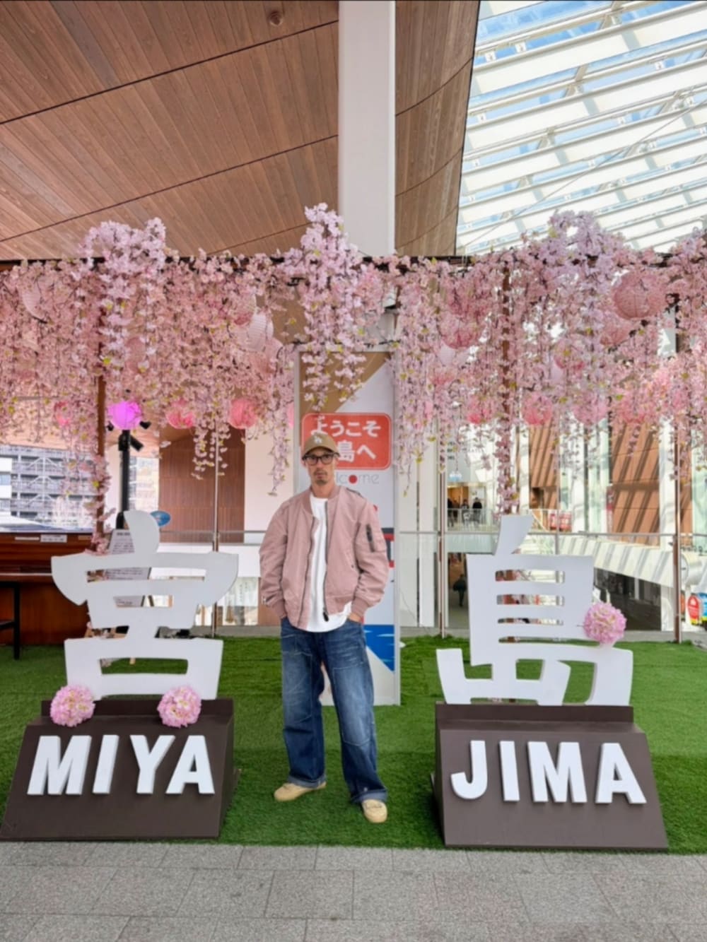 ピンク系のミリタリージャケット、ブルー系のデニムパンツ、ベージュ系のスニーカーを着用したメンズの春コーディネートの3枚目の写真