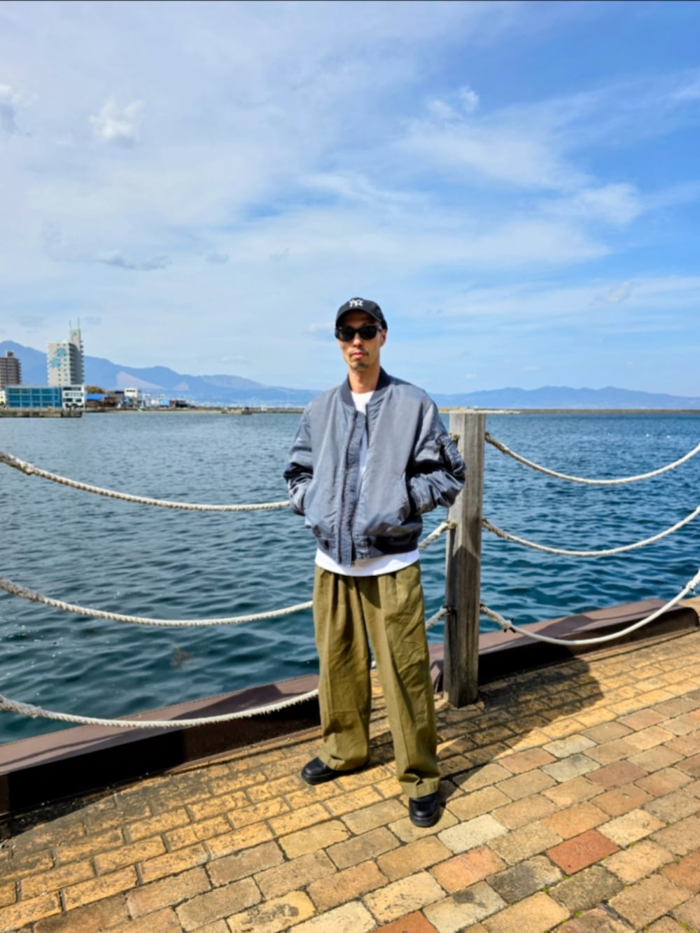 ブルー系のMA-1、グリーン系のスラックス、ブラック系のスニーカーを着用したメンズの冬コーディネートの2枚目の写真