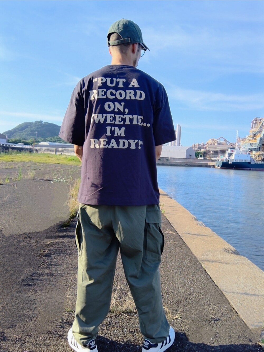 ブラック系のTシャツ/カットソー、グリーン系のカーゴパンツ、ホワイト系のスニーカーを着用したメンズの夏コーディネートの2枚目の写真