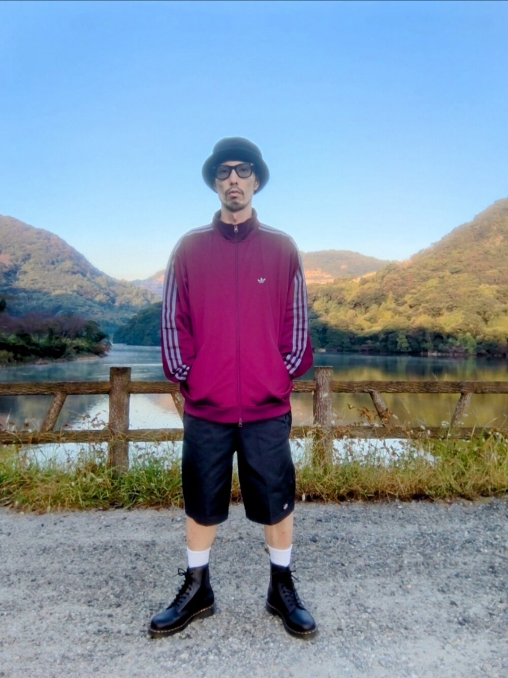 レッド系のジャージ、ブラック系のチノパンツ、ブラック系のブーツを着用したメンズの秋コーディネートの2枚目の写真