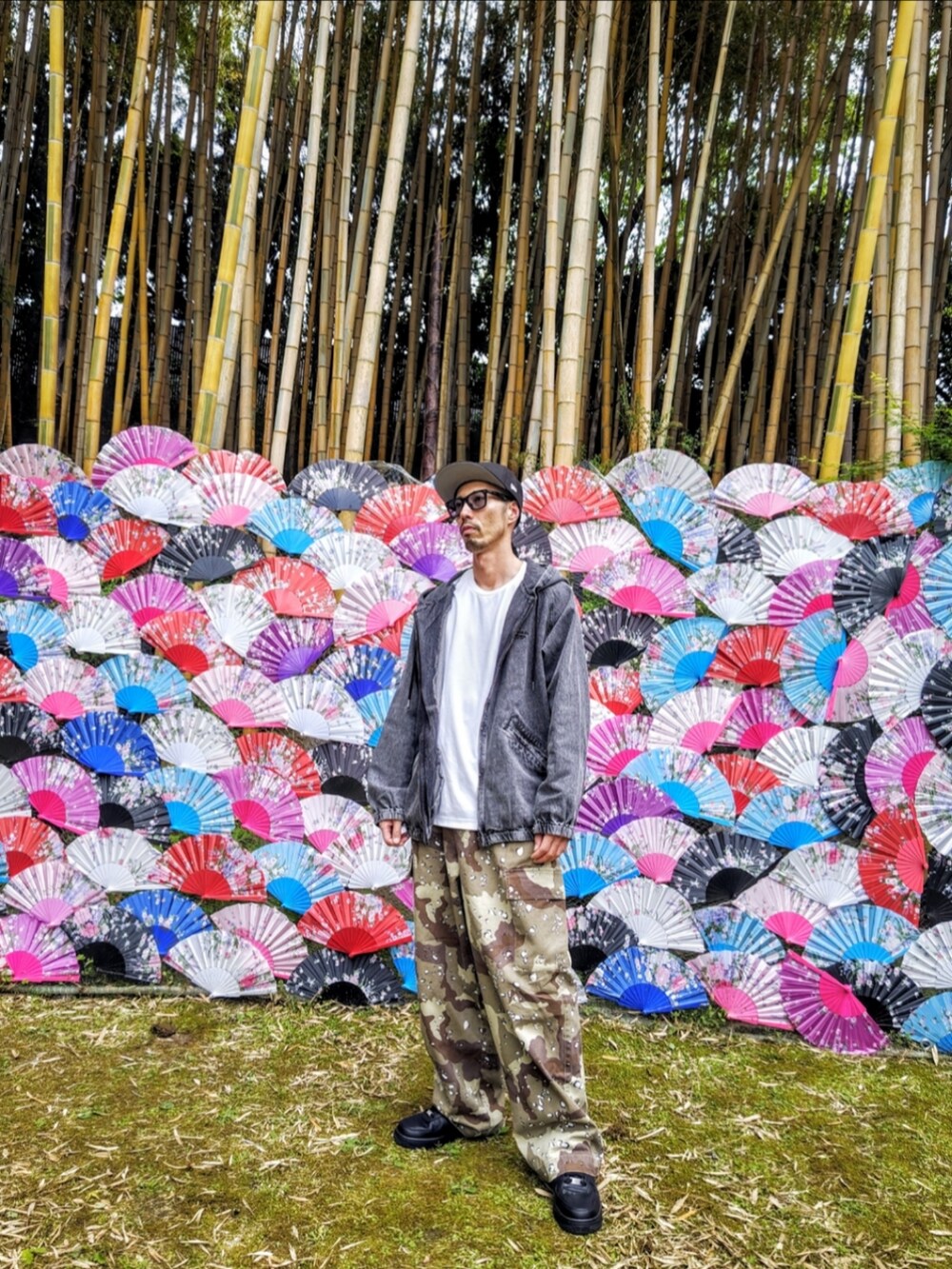 ブラック系のデニムジャケット、グリーン系のカーゴパンツ、ブラック系のスニーカーを着用したメンズの春コーディネートの2枚目の写真