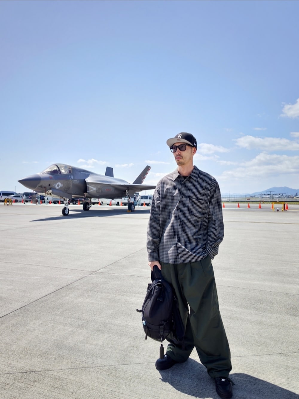 ブラック系のシャツ/ブラウス、ブラック系のバックパック/リュック、グリーン系のカーゴパンツを着用したメンズの春コーディネートの3枚目の写真