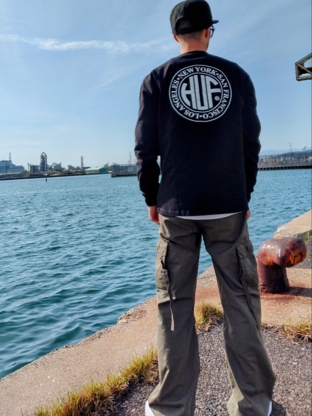 ブラック系のTシャツ/カットソー、グリーン系のカーゴパンツ、ホワイト系のスニーカーを着用したメンズの春コーディネートの3枚目の写真