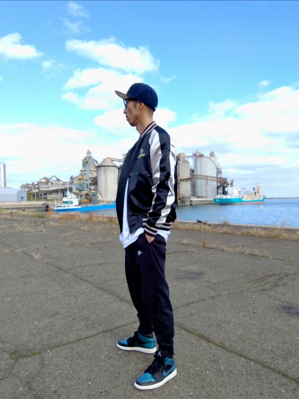 ブラック系のスカジャン、ブラック系のスウェットパンツ、ブルー系のスニーカーを着用したメンズの秋コーディネートの2枚目の写真