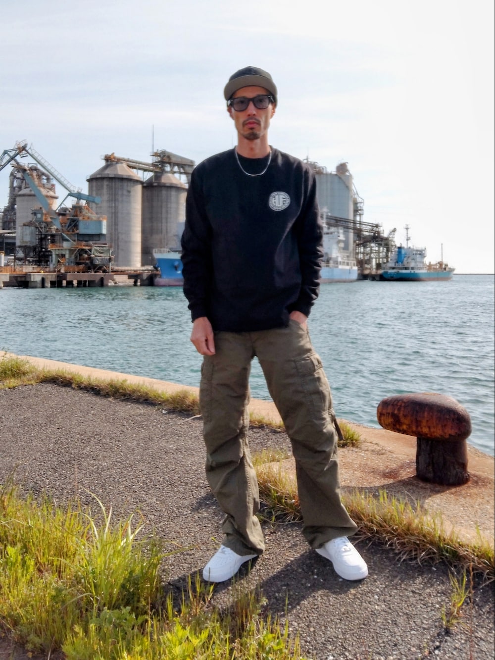 ブラック系のTシャツ/カットソー、グリーン系のカーゴパンツ、ホワイト系のスニーカーを着用したメンズの春コーディネートの2枚目の写真