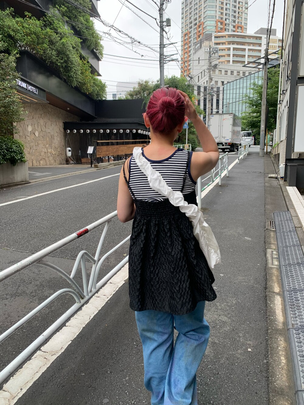 ホワイト系のショルダーバッグ、ブルー系のデニムパンツ、ブラック系のキャミソールを着用したレディースの夏コーディネートの2枚目の写真