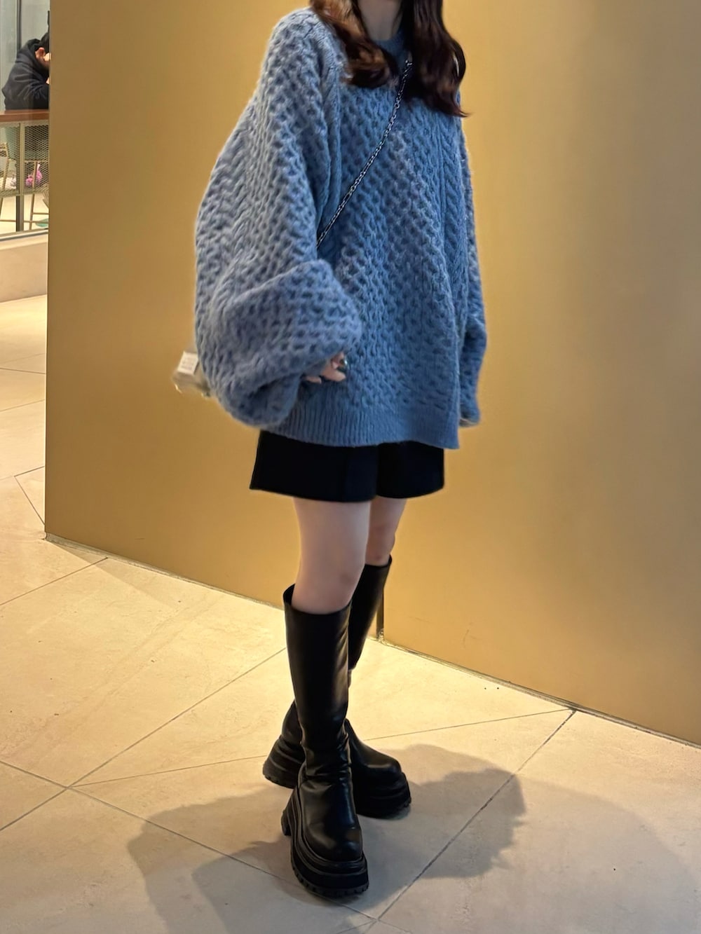 ブルー系のニット/セーター、ブラック系のブーツ、ブラック系のショルダーバッグを着用したレディースの秋コーディネートの3枚目の写真