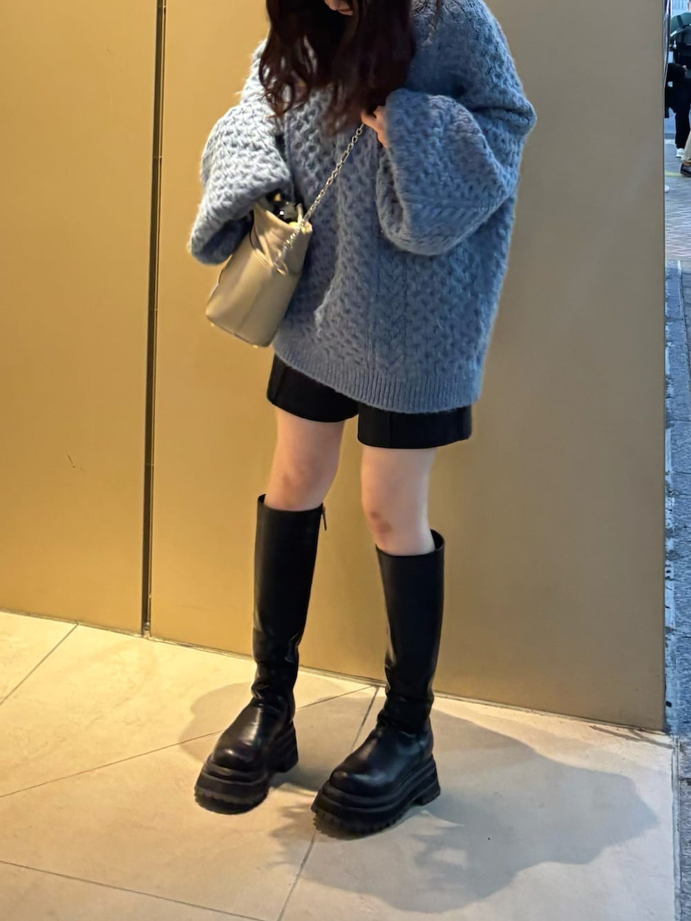 ブルー系のニット/セーター、ブラック系のブーツ、ブラック系のショルダーバッグを着用したレディースの秋コーディネートの2枚目の写真