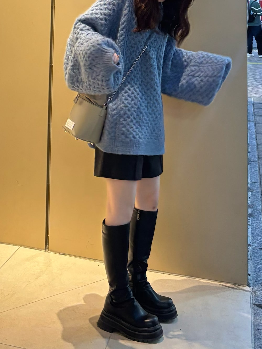 ブルー系のニット/セーター、ブラック系のブーツ、ブラック系のショルダーバッグを着用したレディースの秋コーディネートの4枚目の写真