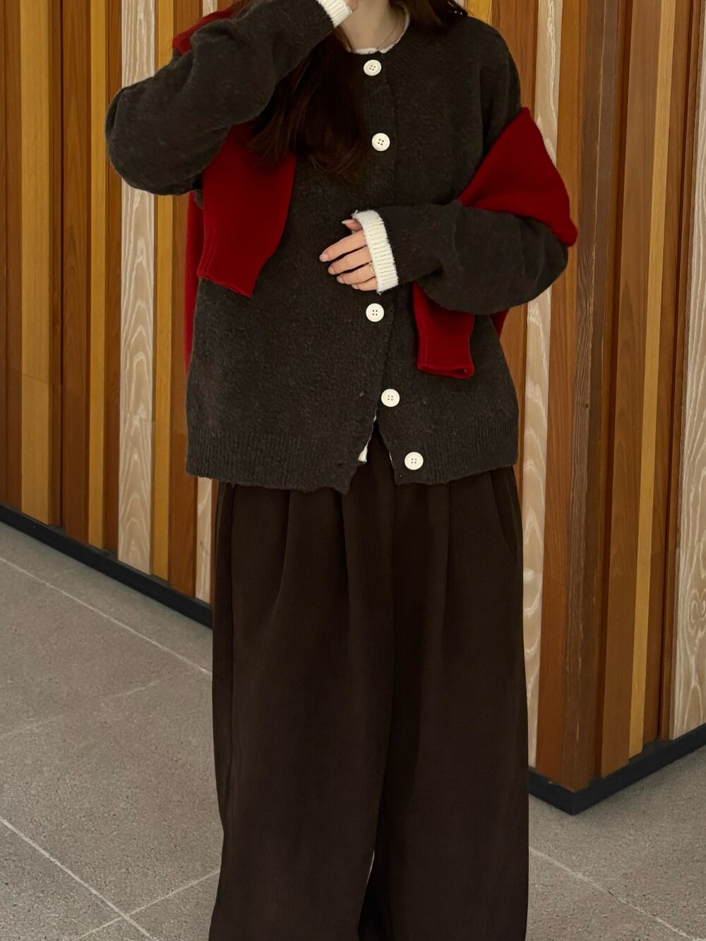 レッド系のニット/セーター、ブラウン系のニット/セーター、イエロー系のブーツを着用したレディースの冬コーディネートの2枚目の写真