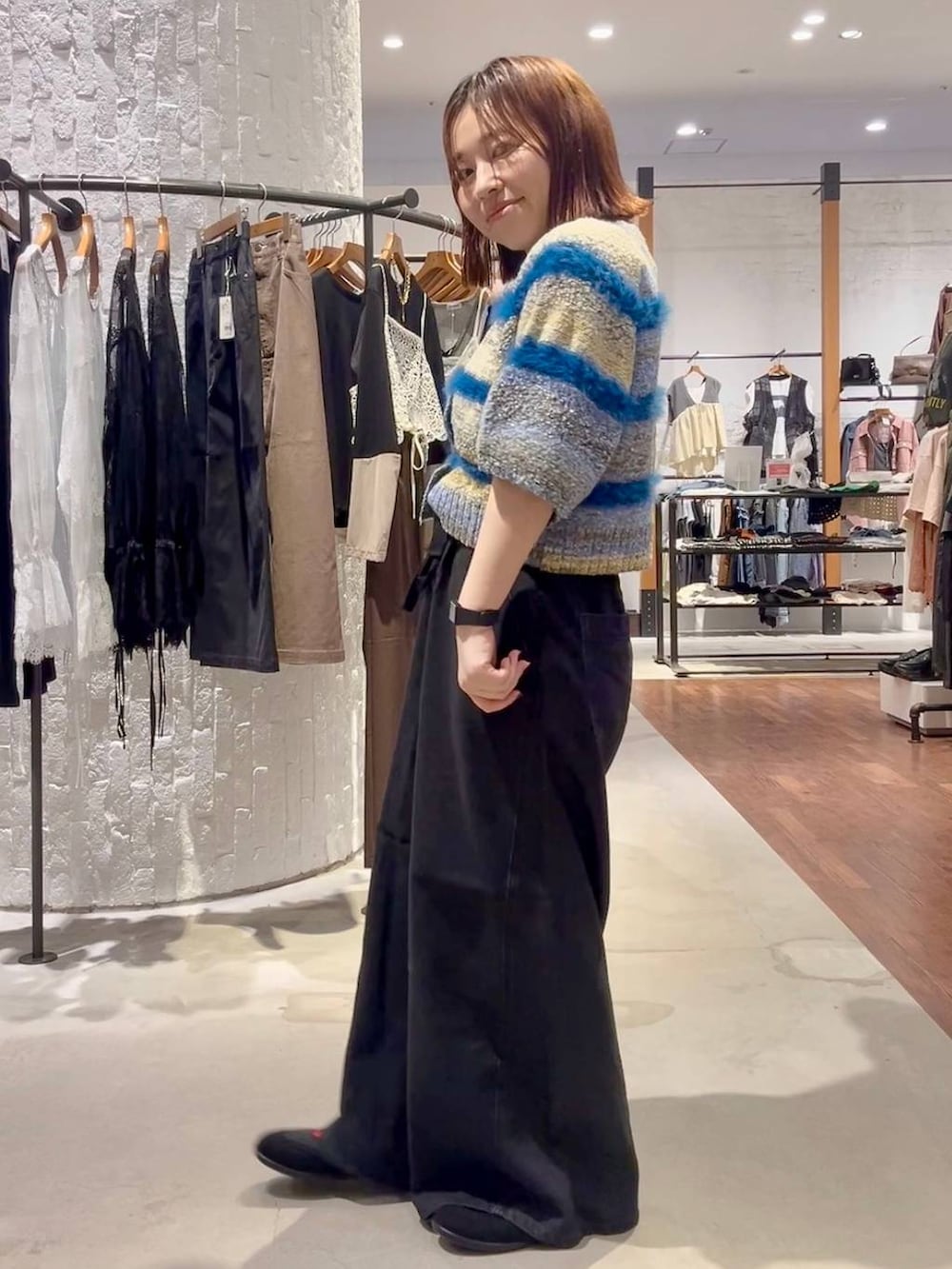 ブラック系のパンプス、ブルー系のニット/セーター、ブラック系のデニムパンツを着用したレディースの夏コーディネートの3枚目の写真