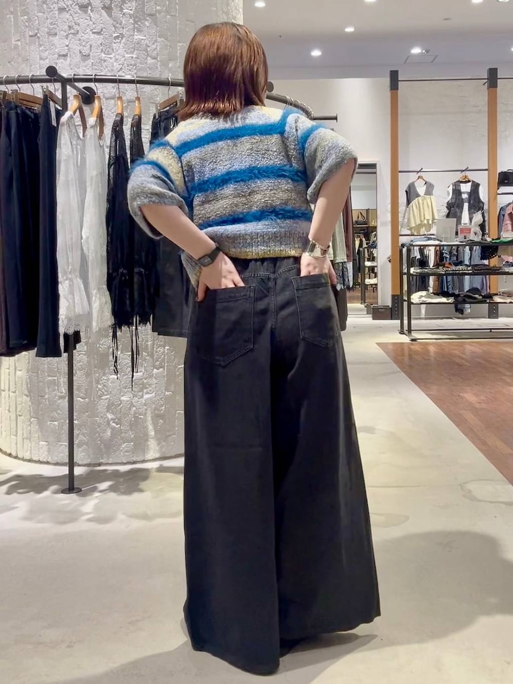 ブラック系のパンプス、ブルー系のニット/セーター、ブラック系のデニムパンツを着用したレディースの夏コーディネートの5枚目の写真