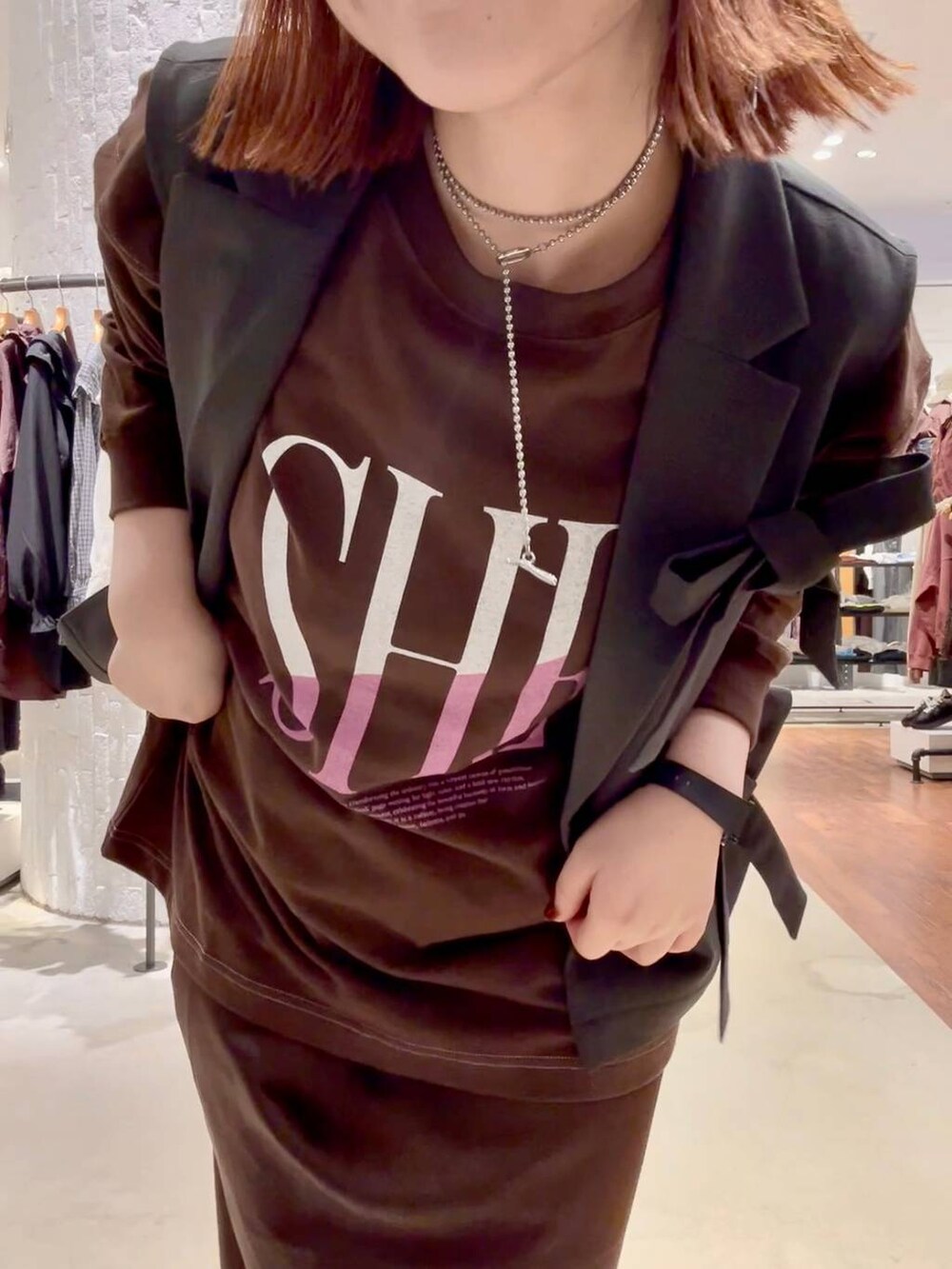 ブラウン系のスカート、ブラウン系のTシャツ/カットソー、レッド系のスニーカーを着用したレディースの秋コーディネートの5枚目の写真