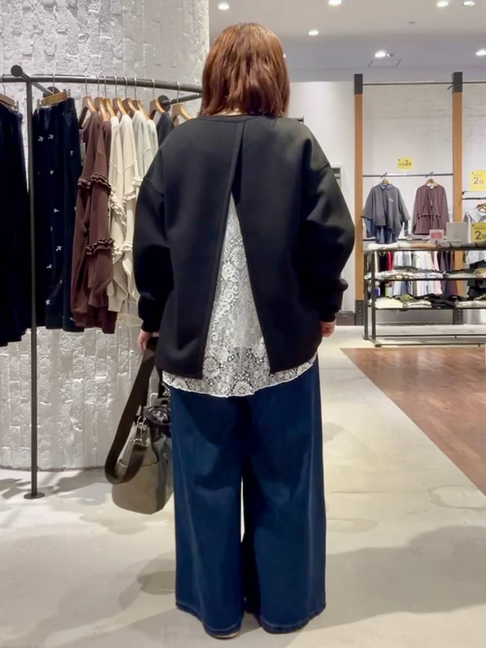 ブルー系のスニーカー、グリーン系のショルダーバッグ、ブルー系のデニムパンツを着用したレディースの秋コーディネートの4枚目の写真