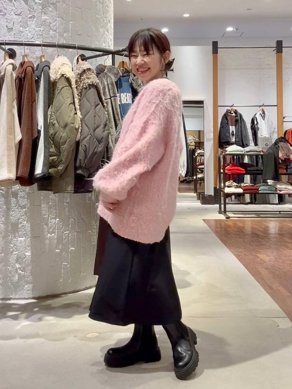 グレー系のニット/セーター、ブラック系のブーツ、ピンク系のカーディガン/ボレロを着用したレディースの冬コーディネートの3枚目の写真