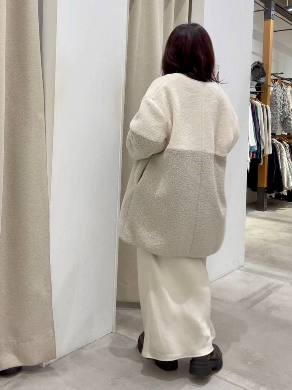 ホワイト系のスカート、ホワイト系のその他アウター、ブラウン系のブーツを着用したレディースの秋コーディネートの5枚目の写真