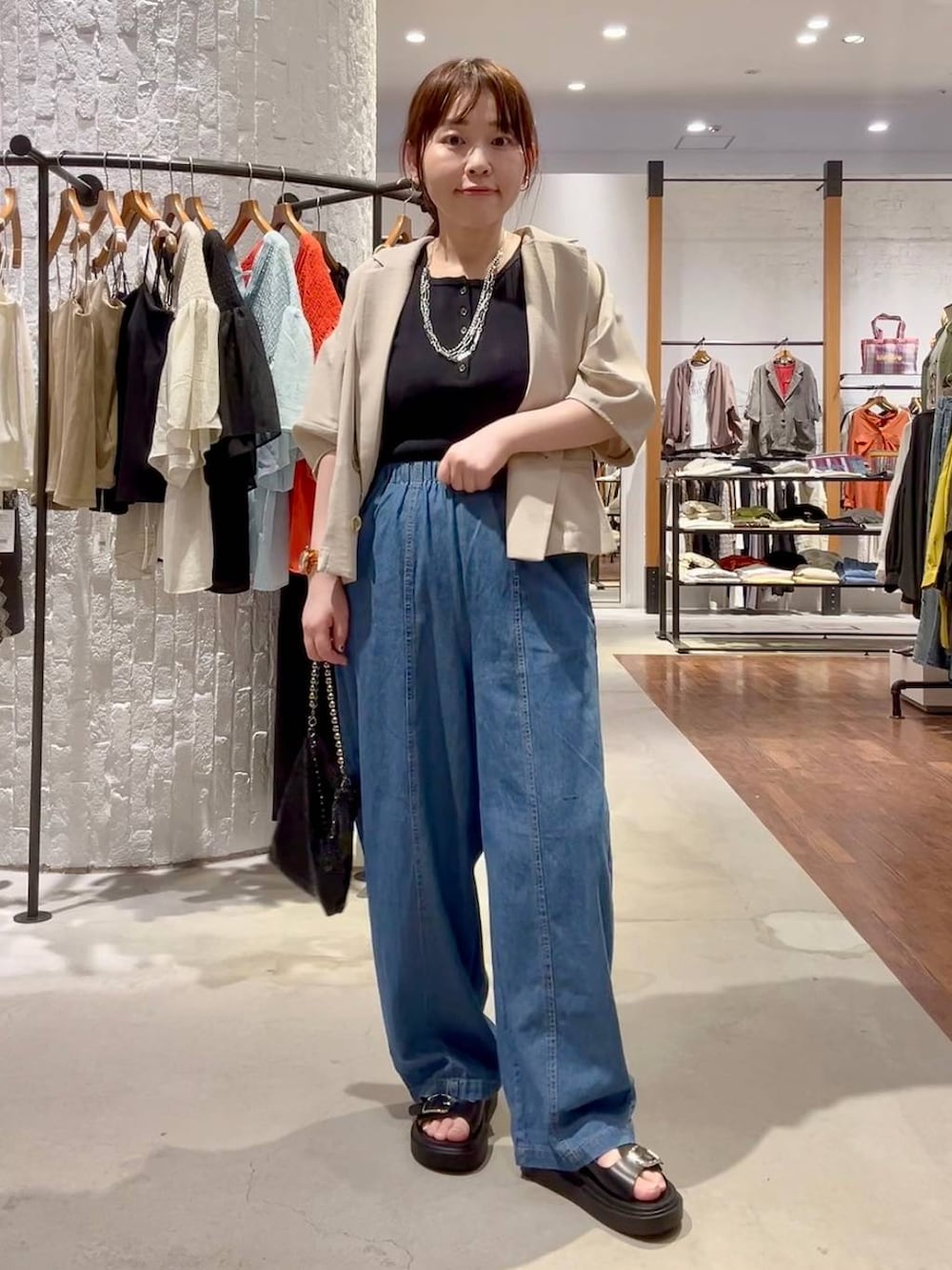 ブラック系のサンダル、ベージュ系のテーラードジャケット、ブラック系のショルダーバッグを着用したレディースの春コーディネートの2枚目の写真