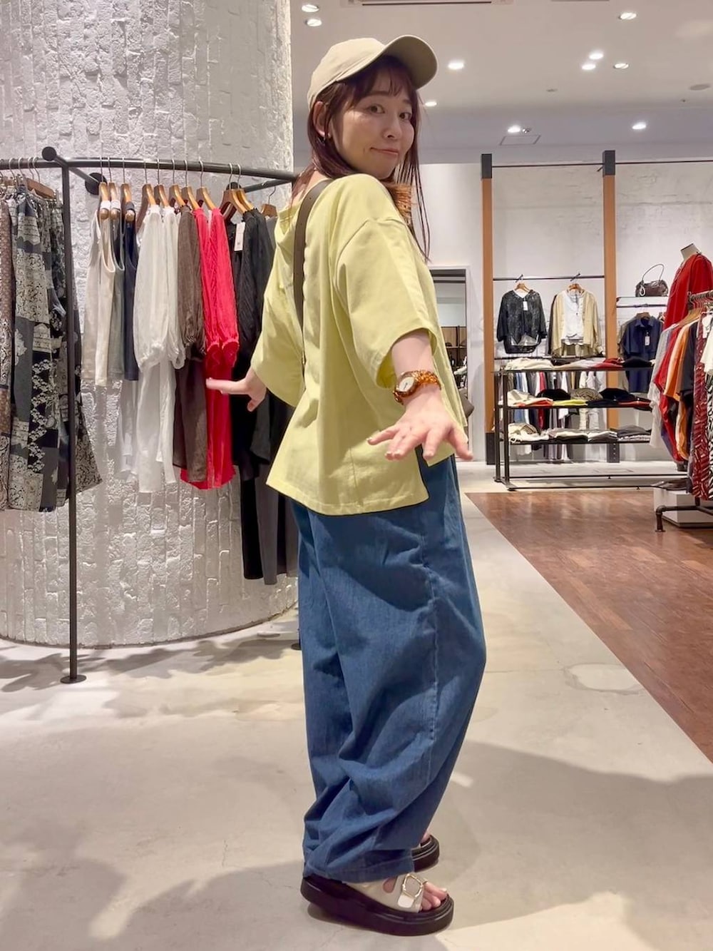 ブラウン系のショルダーバッグ、ホワイト系のサンダル、ブルー系のデニムパンツを着用したレディースの春コーディネートの5枚目の写真