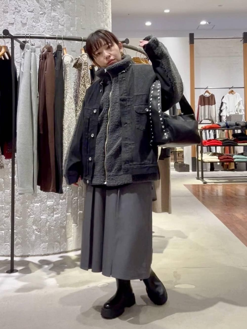 ブラック系のブーツ、ブラック系のデニムジャケット、ブラック系のハンドバッグを着用したレディースの秋コーディネートの2枚目の写真