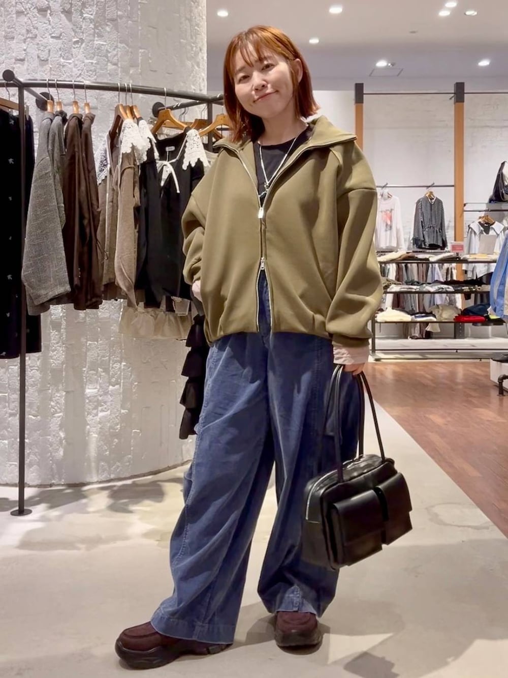 ブラウン系のローファー、ブルー系のその他パンツ、ブラック系のボストンバッグを着用したレディースの秋コーディネートの2枚目の写真