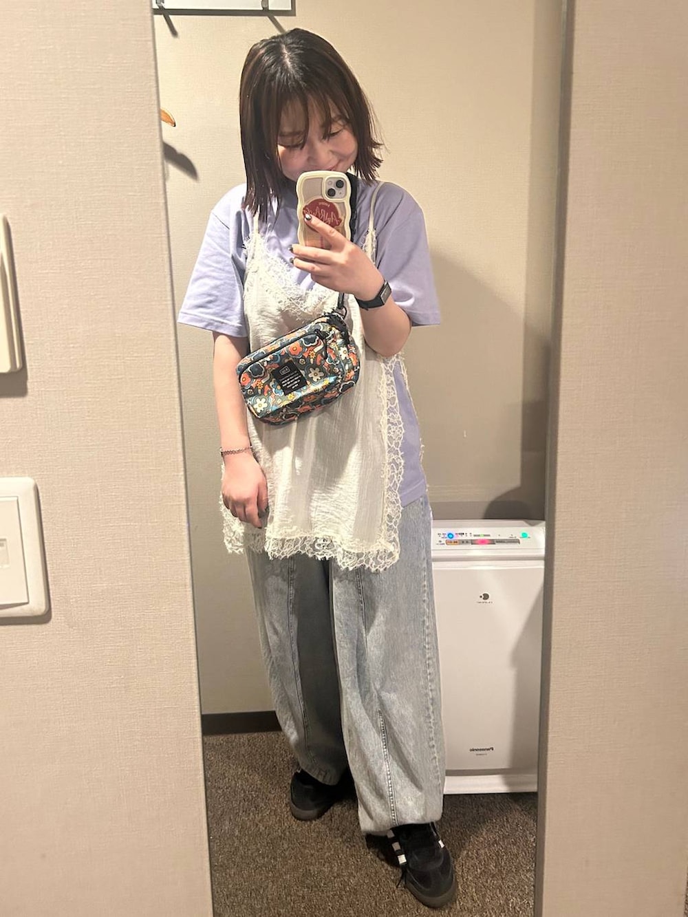 パープル系のトートバッグ、ブラック系のスニーカー、ブルー系のデニムパンツを着用したレディースの夏コーディネートの5枚目の写真