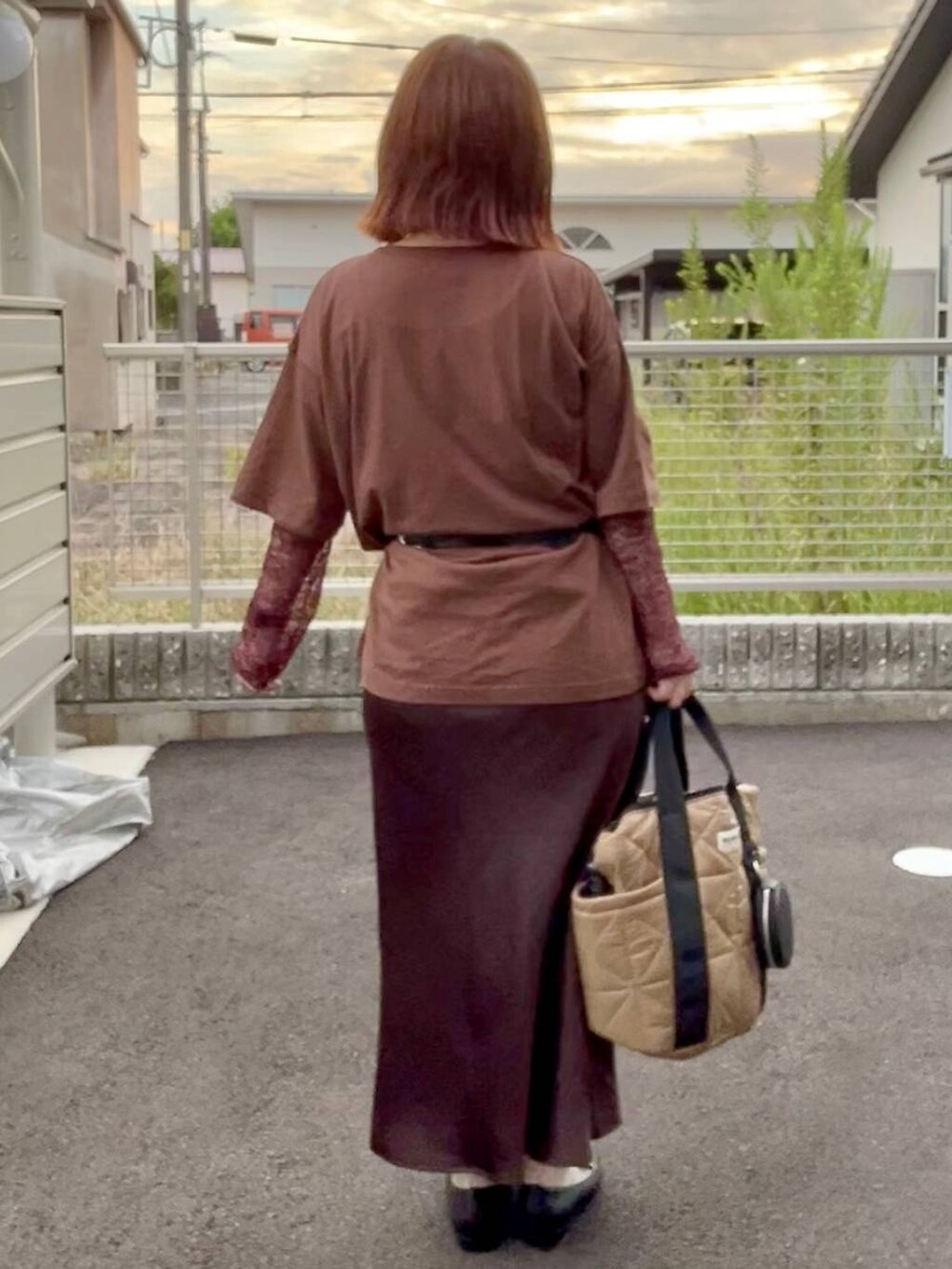 ブラウン系のスカート、ブラウン系のTシャツ/カットソー、ゴールド系のネックレスを着用したレディースの秋コーディネートの4枚目の写真