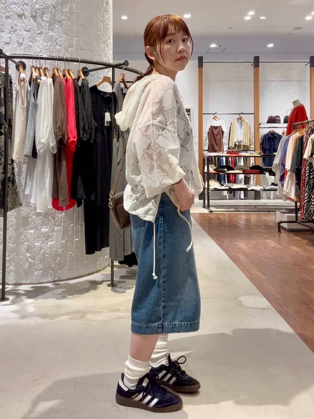 ブラック系のスニーカー、ブラウン系のショルダーバッグ、ブルー系のデニムパンツを着用したレディースの春コーディネートの3枚目の写真